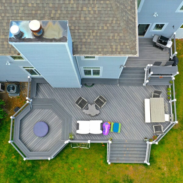 Top-Down Aerial View Of A Large Custom Grey Composite Deck Featuring An Octagonal Lounge Platform Outdoor Dining Set Grill Area And White Railings