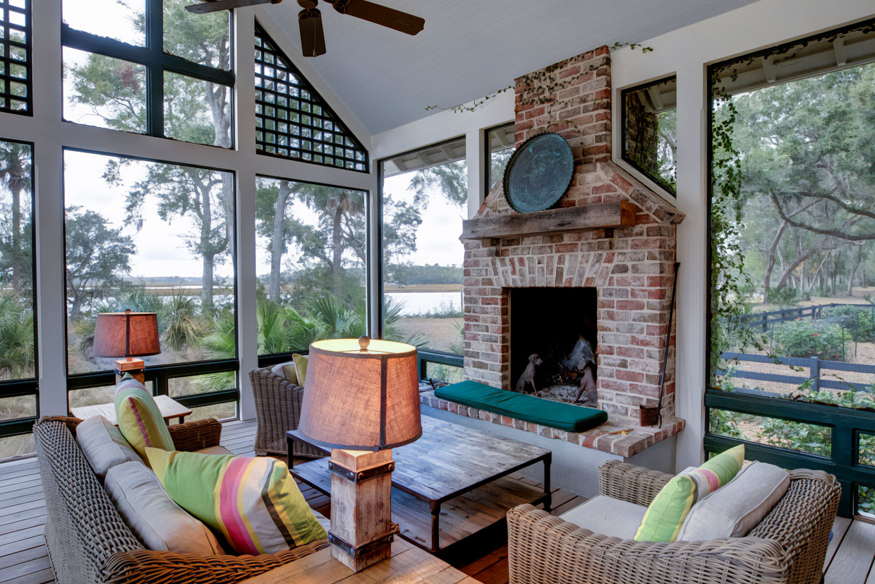 High-End Sunroom Design Ideas For Decks Featuring A Brick Fireplace, Tall Windows, And Wicker Furniture With Colorful Cushions.