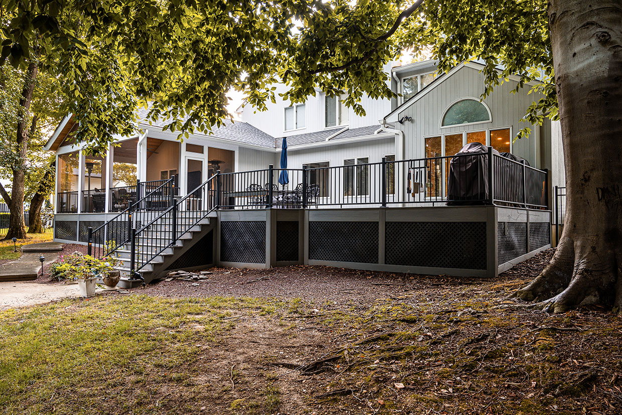 A Completed Grey Composite Deck With Black Railings And A Screened-In Porch, Illustrating The Results Of A Timely Seasonal Deck Construction Checklist.