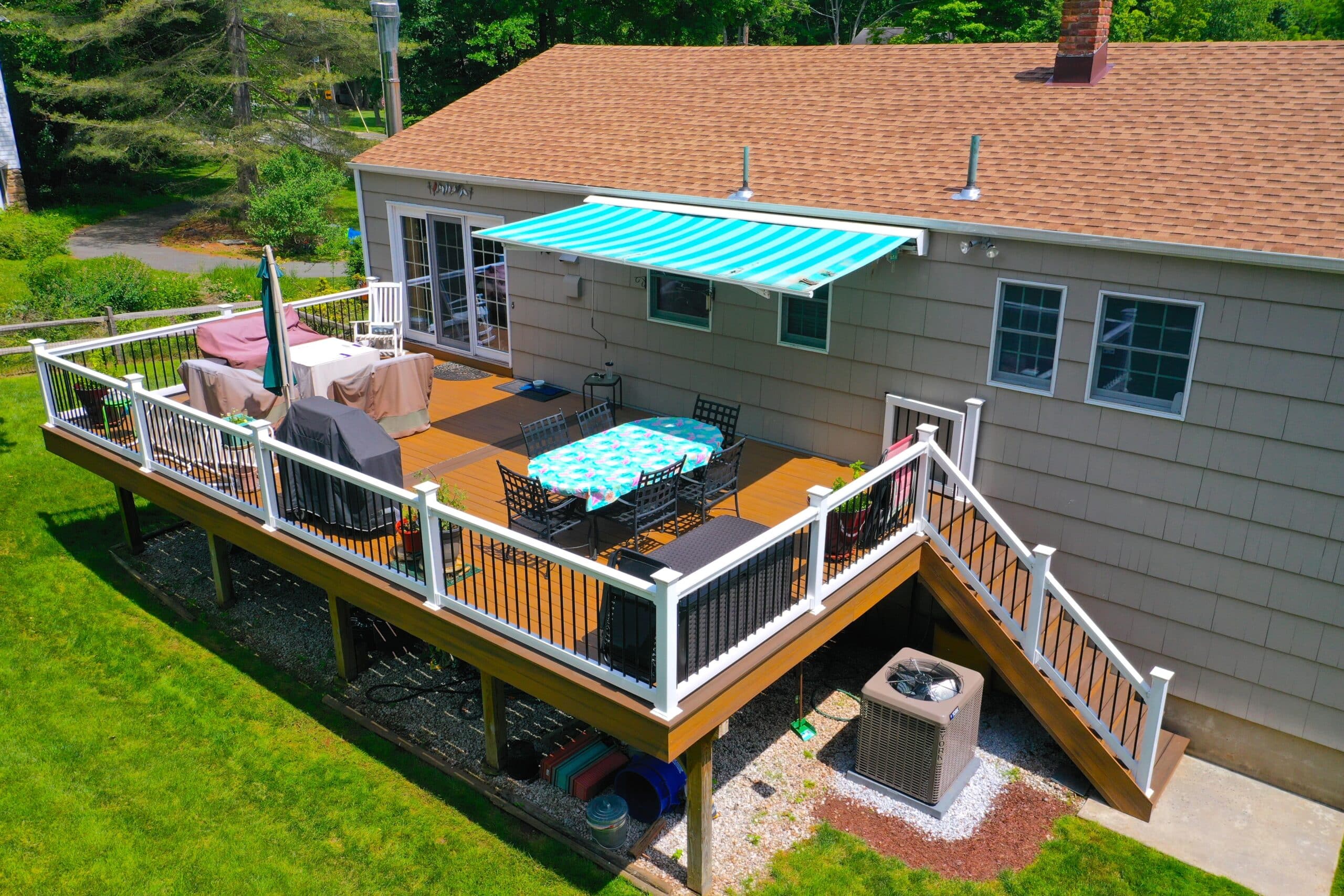 Spacious Multi-Level Deck With Dark Wood Finishes, Black Railings, And Stairs Connecting Various Levels, Ideal For Relaxing Outdoors.