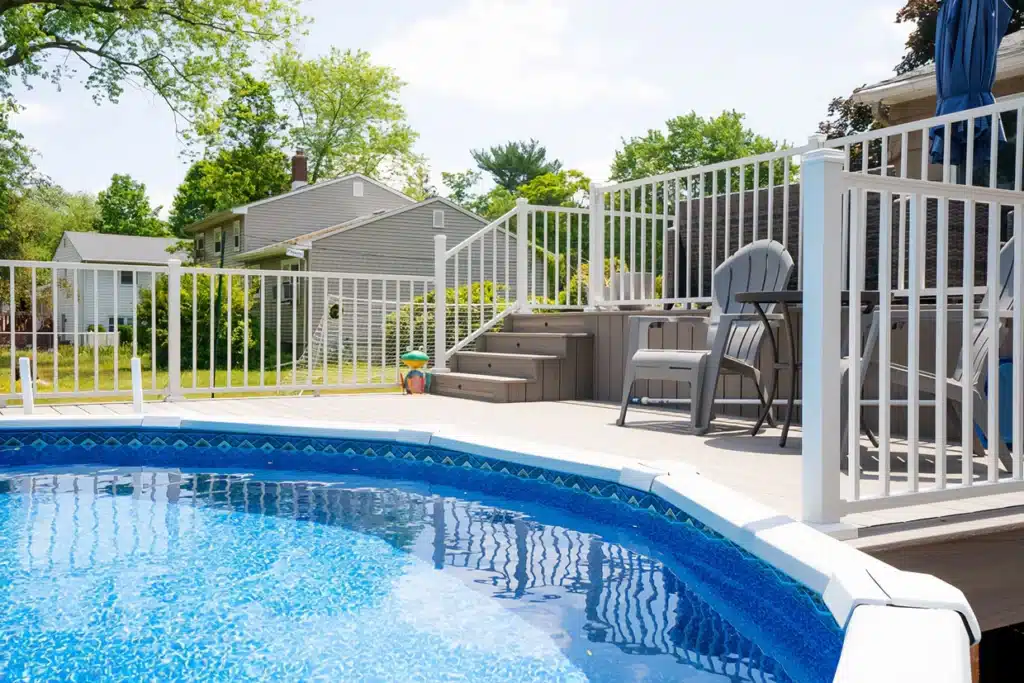 Pool deck coating on the poolside with a white fence and cozy seating area, offering a perfect space for relaxation and enjoyment.