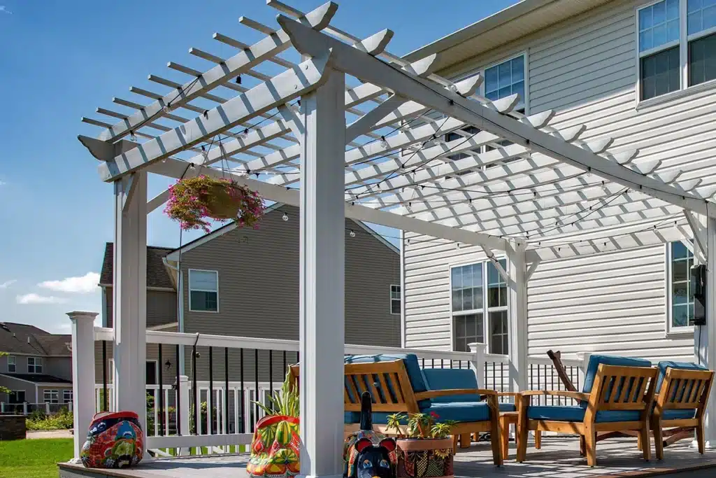 A spacious backyard with a pergola, deck, and outdoor kitchen, featuring pergola louvers for shade.