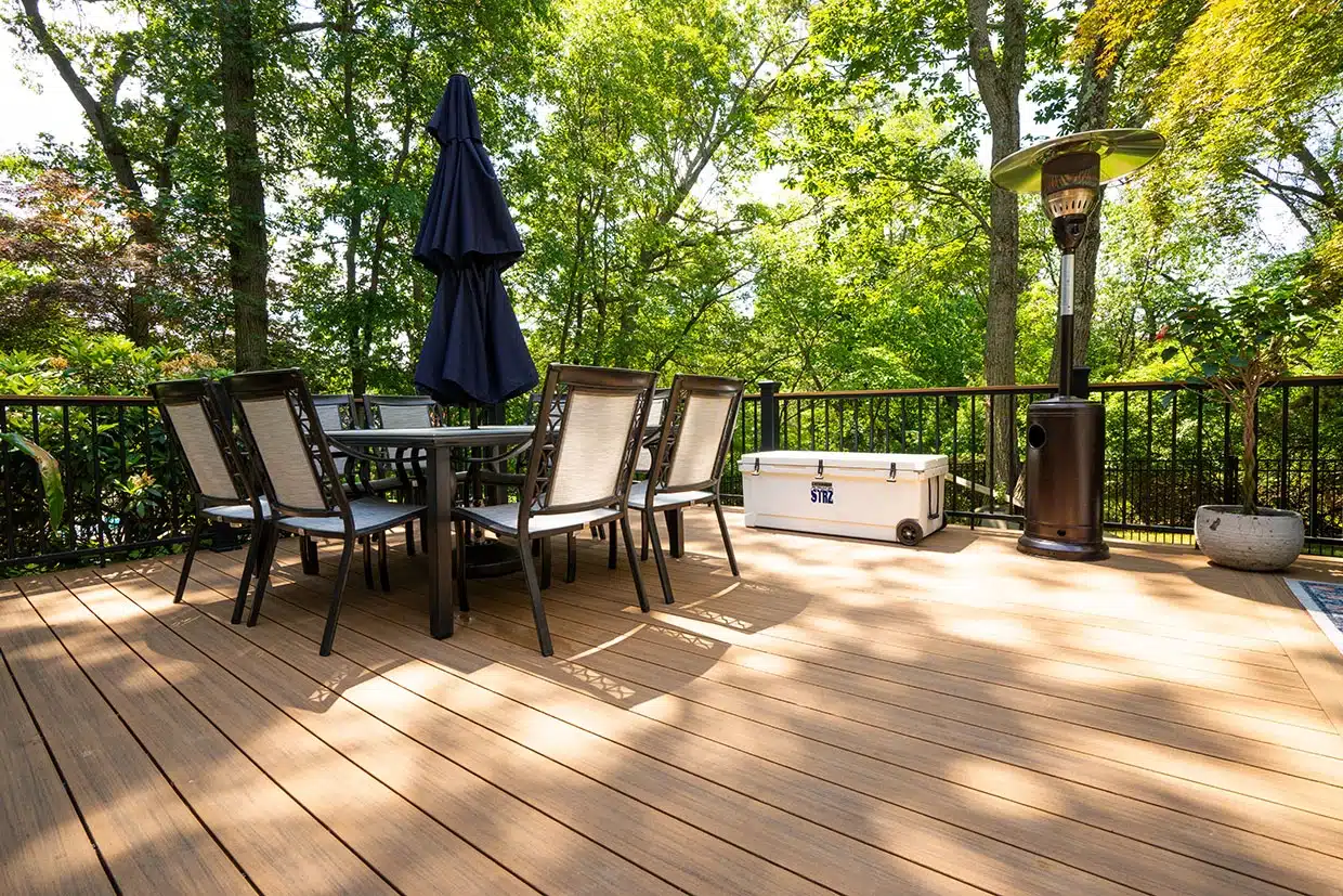 composite vs wood decks 1 A Composite Deck Featuring A Dining Set, Cooler, And Outdoor Heater, Showcasing The Benefits Of Composite Vs Wood Decks For Backyard Spaces.