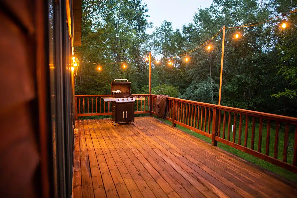 NJ Patio Installation 4 A Cozy Wooden Deck With String Lights And A Grill, Perfect For Nj Patio Installation.