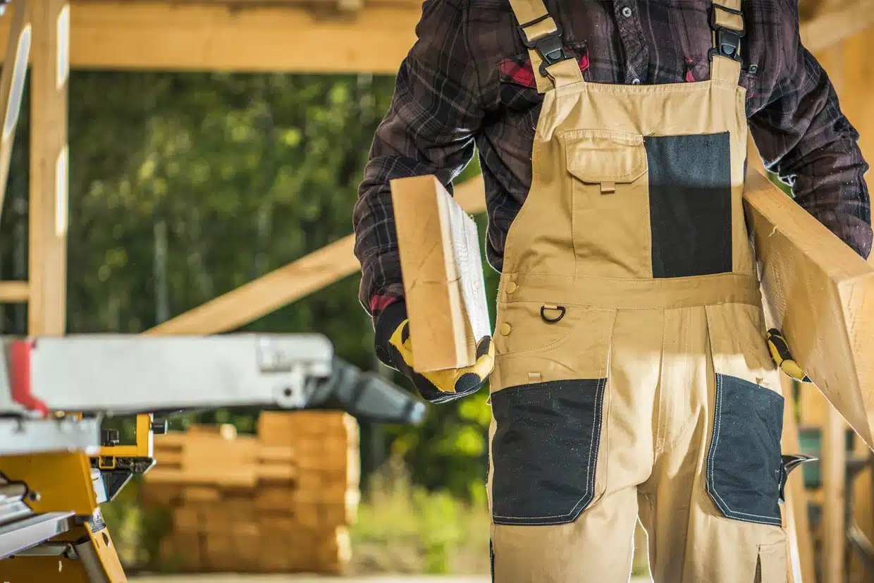 choosing a deck builder 3 A Worker Carrying Wooden Planks At A Construction Site, Ready For Deck Building, Choosing A Deck Builder For Quality Materials