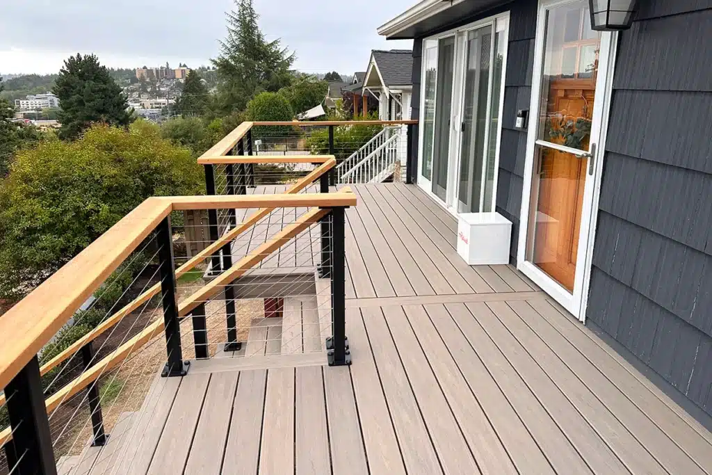 A Well-Designed Deck With Wood Railing And Cable Wire Details, Overlooking A Scenic Landscape, Showcasing Deck Systems For Sloped Yards.