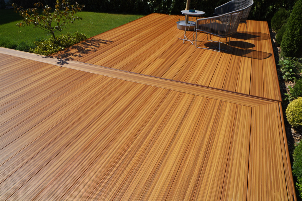 A wide, modern ground level deck made of rich caramel-toned bamboo decking boards with a picture frame border layout.
