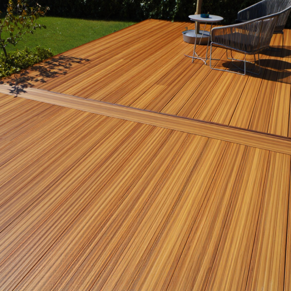 A wide, modern ground level deck made of rich caramel-toned bamboo decking boards with a picture frame border layout.